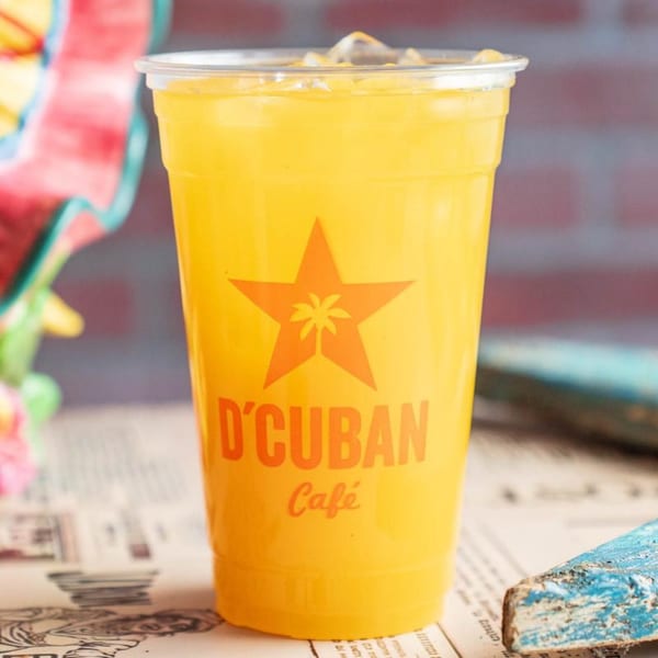 A D'Cuban Cafe branded cup filled with a vibrant yellow drink and ice.