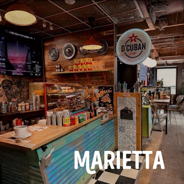 Interior of D'Cuban Cafe with a corrugated metal counter, pastries, and a D'Cuban Cafe sign.