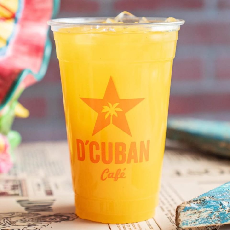 A D'Cuban Cafe branded cup filled with a vibrant yellow drink and ice.