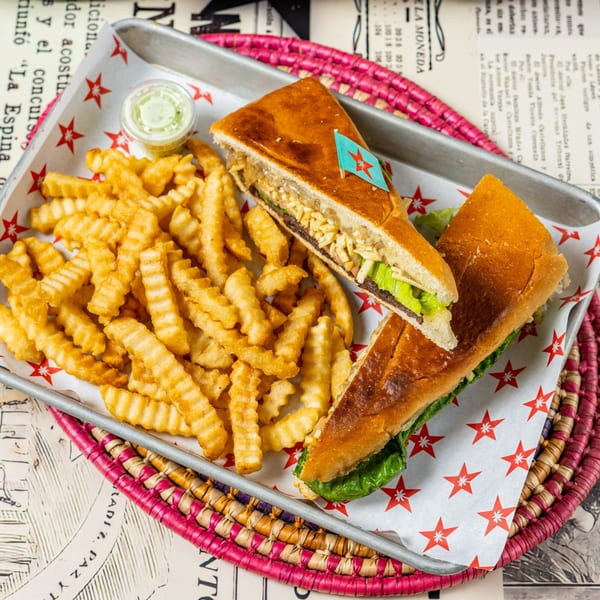 A D'Cuban Cafe Cuban sandwich with fries and dipping sauce on a star-patterned tray.