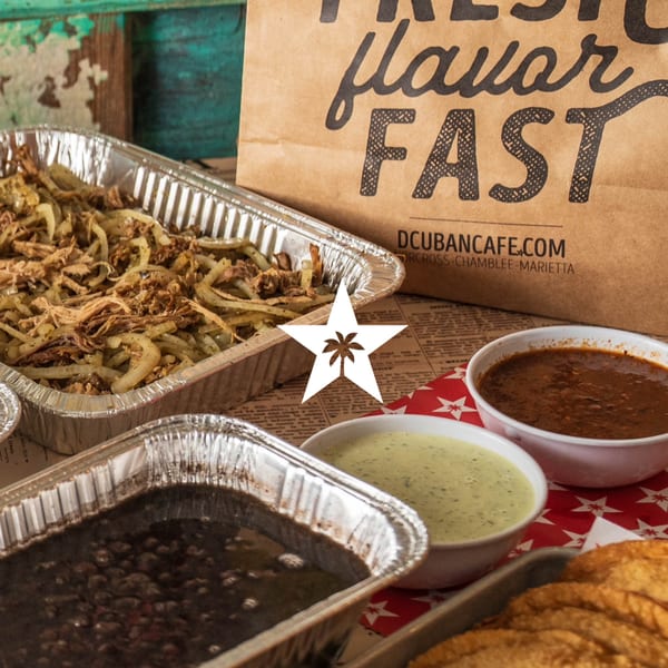 D'Cuban Cafe's Cuban food spread with shredded pork, black beans, sauces, and a takeout bag.