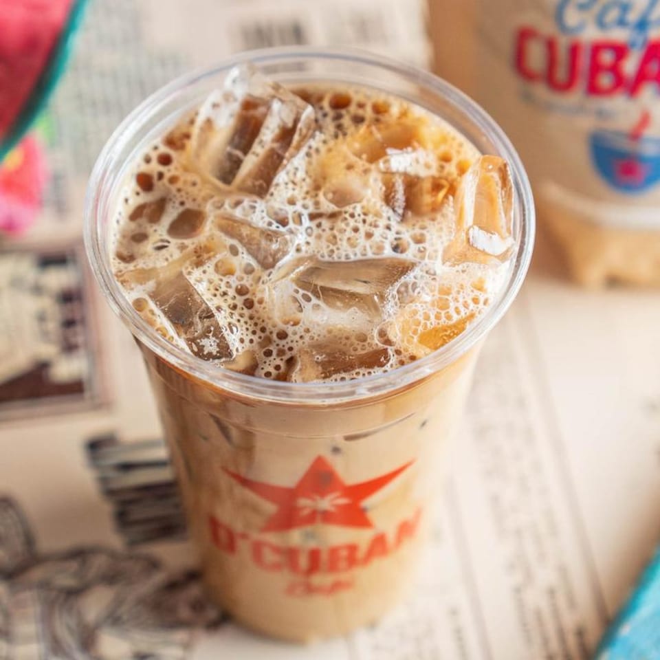 Iced D'Cuban Cafe coffee with ice and foam, featuring the red star logo on the cup.