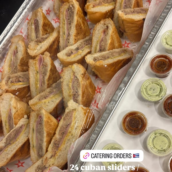 A catering tray of D'Cuban Cafe's Cuban sliders, individually wrapped, with small sauce containers.